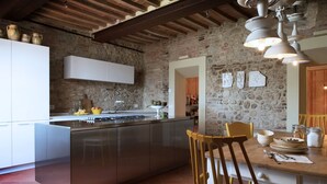 Une cuisine moderne dotée d’un îlot central, de meubles blancs et d’un mur en pierre en arrière-plan.
