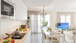 A modern kitchen with a dining area, a TV, and a view of the outdoors.