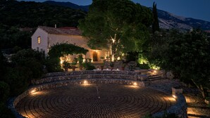 A stone courtyard with a circular pattern, surrounded by a stone wall and potted plants. - High-end, sea view, 5 bed villa with Chef, maid, large pool + skippered boat (Moussata)