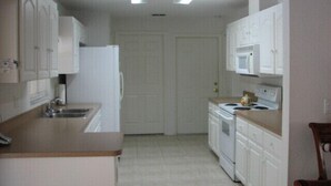 A compact kitchen with white cabinets, a refrigerator, a microwave, and a stove.