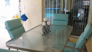 A glass-top table with four chairs, each with a teal cushion.