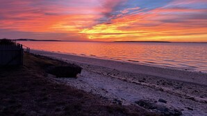 A beach with a wooden fence and a rocky foreground. - Hamptons Waterfront Beach Home With Dock (Southampton)