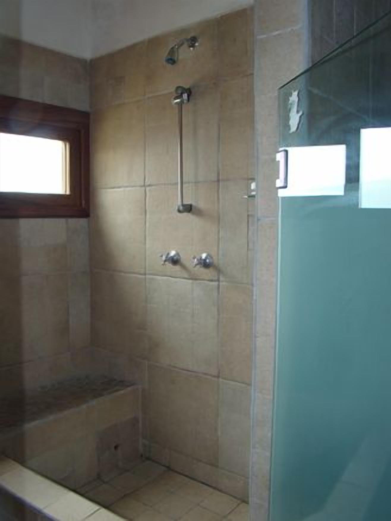 A bathroom with a shower, a window, and a glass door.