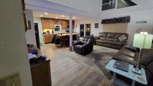 A spacious living area with a high ceiling, a kitchen in the background, and a cozy seating area with a sofa and chairs. - Paradise - Coldwater/North Lake Rental - Monthly/Weekly /4 day off season (Coldwater)