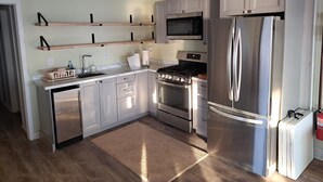 A modern kitchen with stainless steel appliances, wooden shelves, and a microwave. - Paradise - Coldwater/North Lake Rental - Monthly/Weekly /4 day off season (Coldwater)