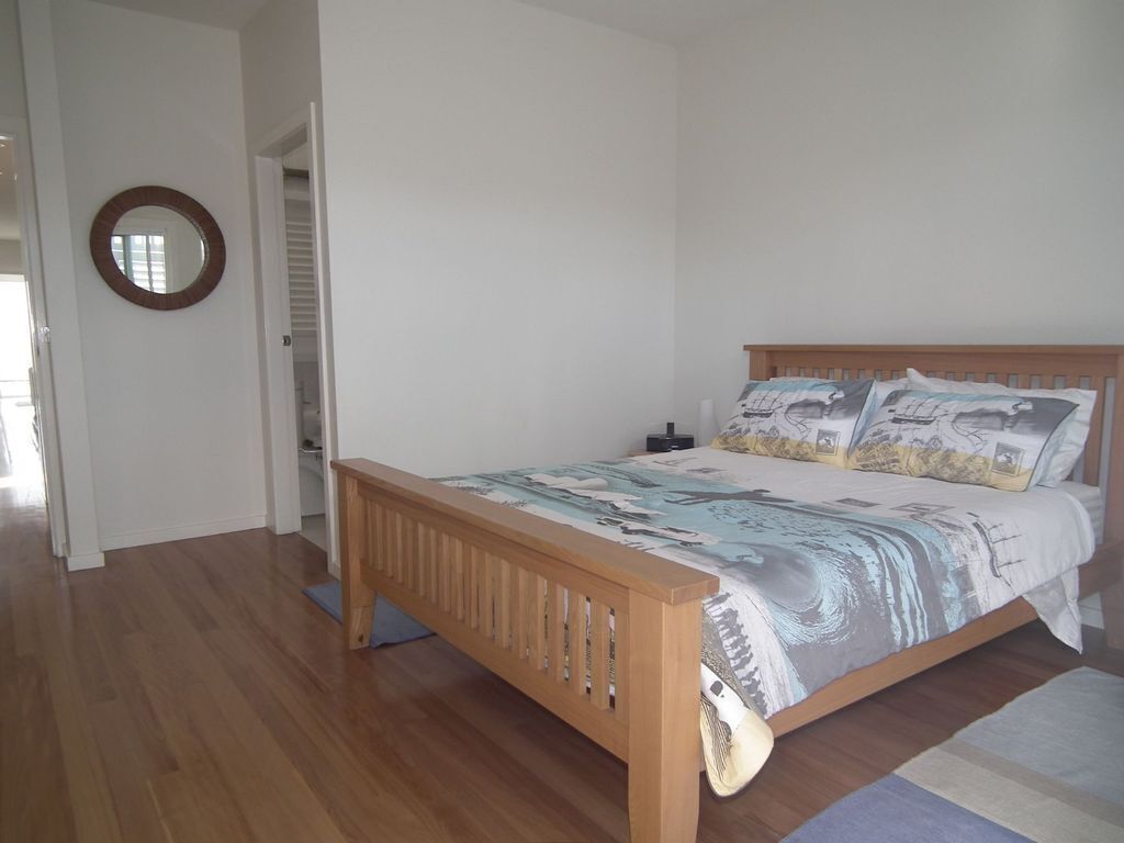 A bedroom with a wooden bed, a round mirror on the wall, and a view of a staircase.