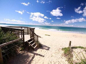 A wooden staircase leading to a beach with clear skies and ocean views. - Absolute Beachfront at Diamond Beach, Luxurious Ocean Views as You Entertain. (Diamond Beach)