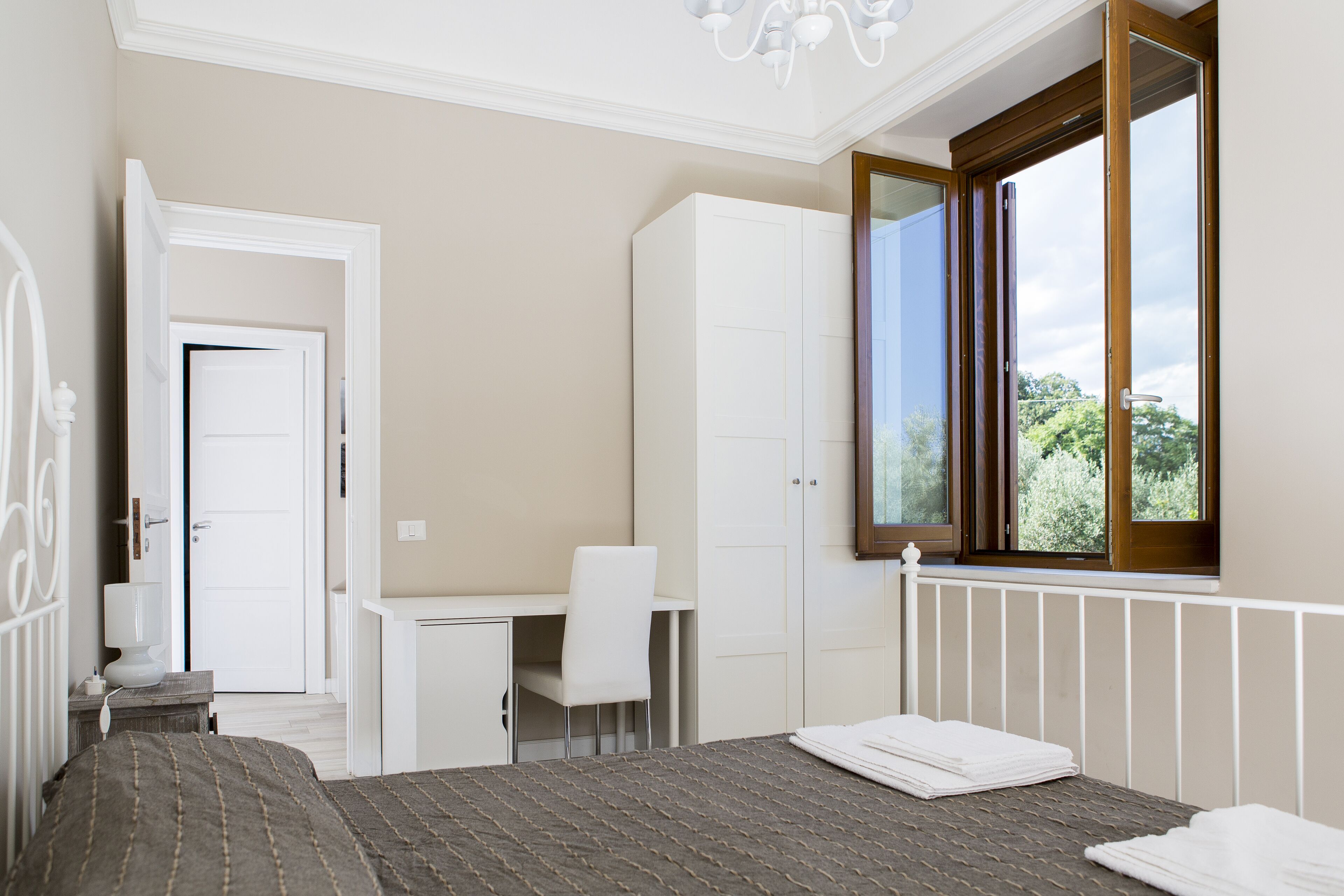 A bedroom with a bed, a desk, and a wardrobe.