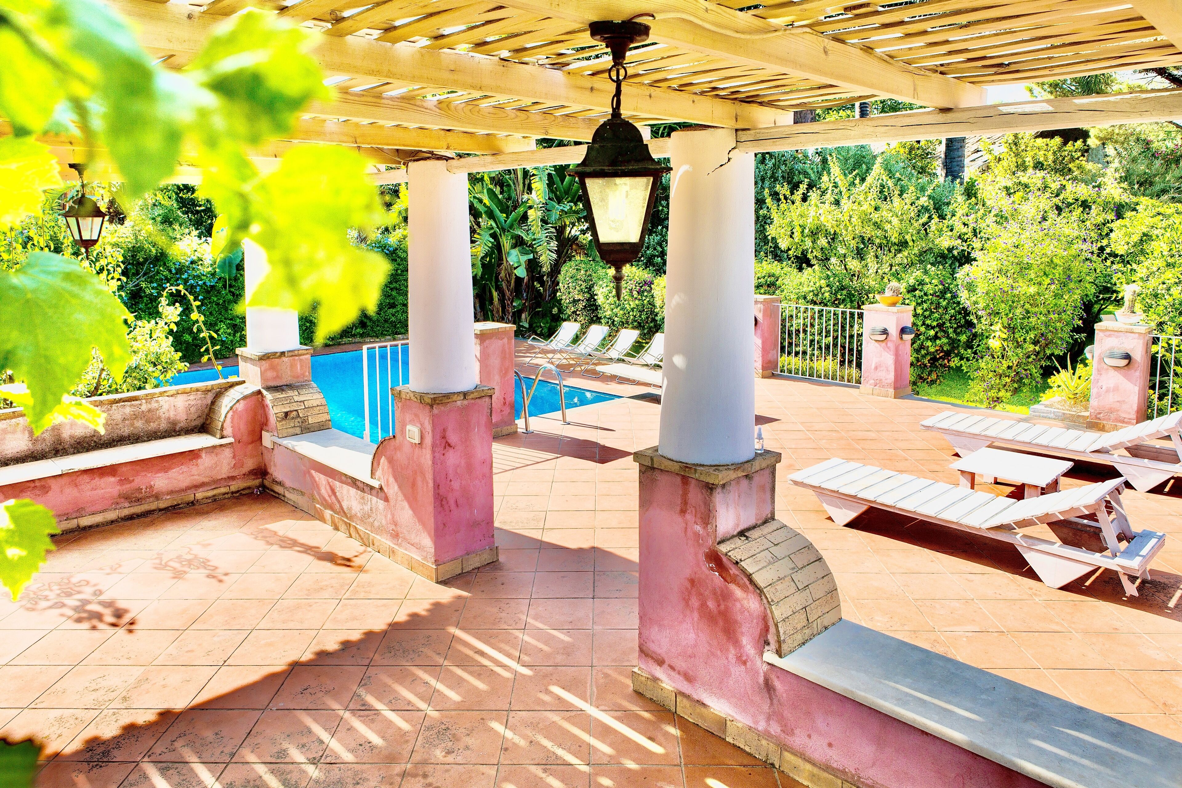 Un espace extérieur abrité comprenant une piscine, des chaises longues et une structure en forme de pergola.