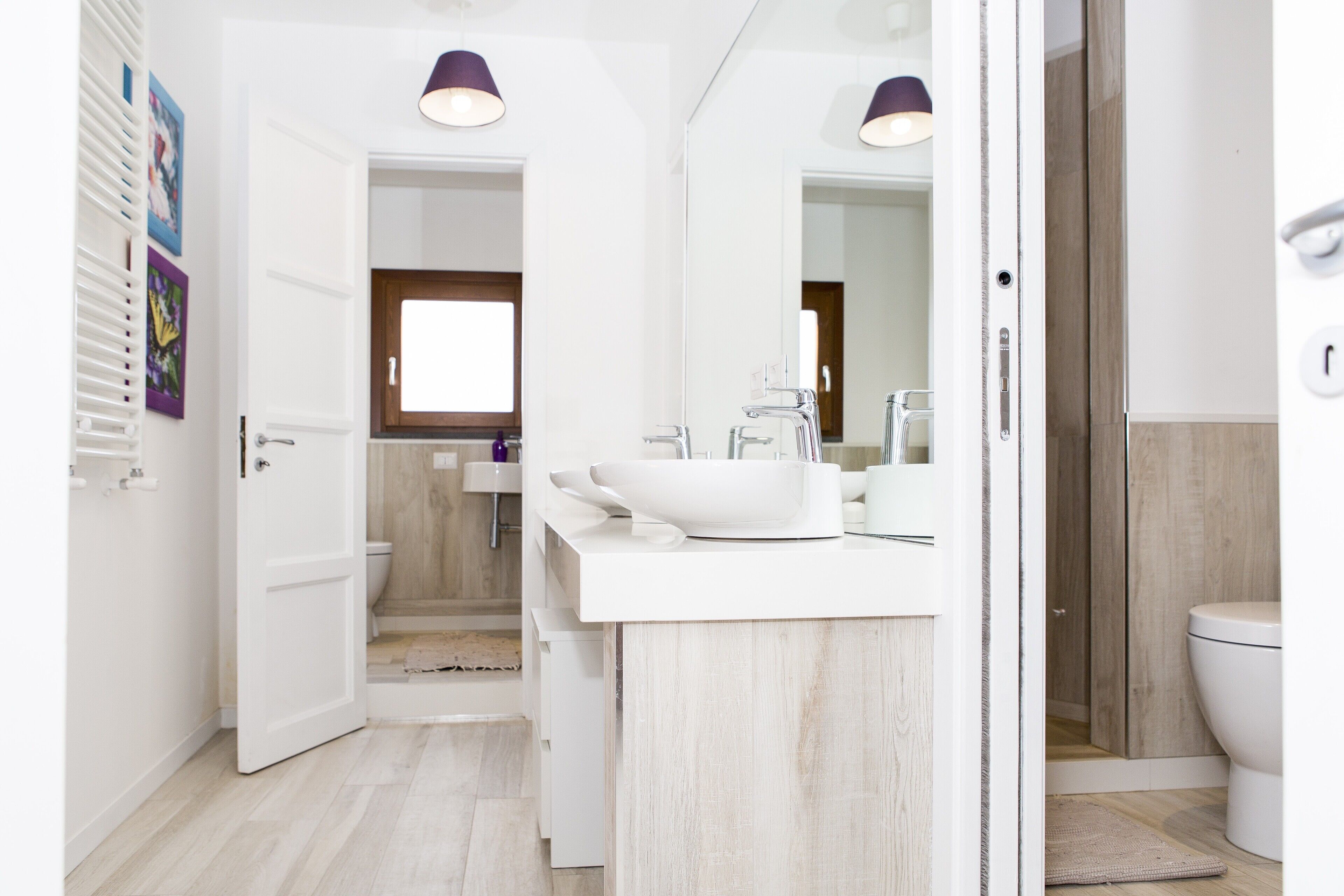 A modern bathroom with a white sink, mirror, and toilet. There is a shower area visible in the background.