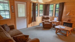 Interior acogedor de una cabaña con un sofá, un sillón y una pequeña mesa de madera.