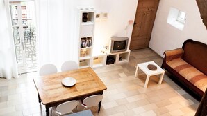 A cozy living room with a wooden table, white chairs, a brown sofa, and a TV on a stand. - Apartment/studio (converted barn, 40 sqm) with gallery (Schernfeld)