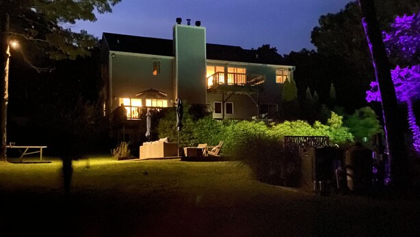 A modern house with a fire pit in the foreground, surrounded by a well-maintained lawn and trees. - 5BR, 5BA on cul-de-sac, Big Pool,  jacuzzi, gym,  beautiful bay beach (Hampton Bays)