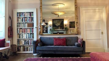 Cozy living space with a large mirror, plush sofa, and bookshelf.