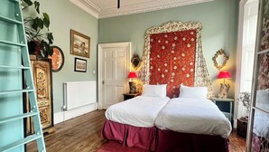 A bedroom with a double bed, a red patterned rug, a ladder, a white radiator, and a ceiling light. - Central Georgian Home with Parking, Art and Antiques (Edinburgh)