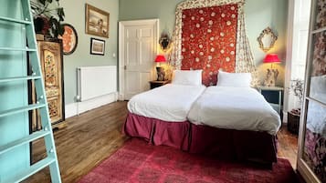 A bedroom with a double bed, a red patterned rug, a ladder, a white radiator, and a ceiling light.