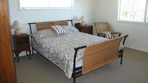 A bedroom with a bed, two bedside tables, a chair, and two windows. - High Street Retreat is set in the heart of Black Head & has magnificent... (Black Head)