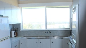 A kitchen with white cabinets, a sink, and a window. - High Street Retreat is set in the heart of Black Head & has magnificent... (Black Head)