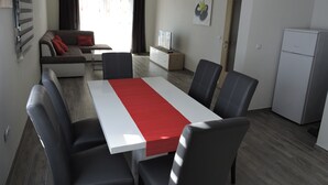 Un soggiorno moderno con un divano, un tavolo da pranzo con sedie, una TV e un frigorifero.