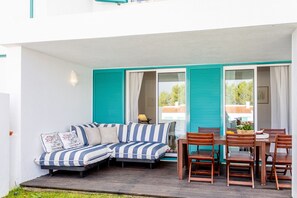 A covered outdoor seating area with a sofa and dining table.