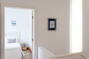 A bedroom with a bed, a bedside table, a framed picture on the wall, and a window with blinds.