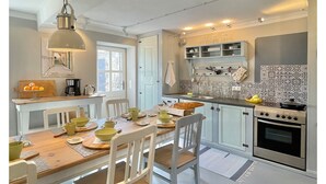 Una cucina moderna con mobili bianchi, un tavolo da pranzo per quattro persone e un forno spazioso.