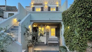 Una casa a due piani con facciata in pietra, un balcone e una scala che conduce all'ingresso.