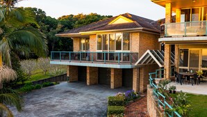 Una casa a due piani con un balcone, un garage e un giardino curato.