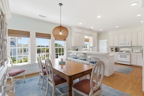 Una cocina amplia con armarios blancos, una mesa de comedor de madera y una isla grande con asientos.