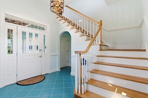 A staircase with wooden steps and white railings, leading to a landing with a white door and a blue-tiled floor.