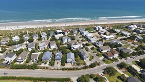 An aerial view of a coastal residential area with houses, a beach, and the ocean.
