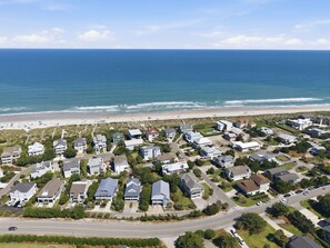 An aerial view of a coastal residential area with houses, a beach, and the ocean.