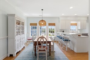 Una cocina amplia con comedor, muebles blancos y una isla grande.