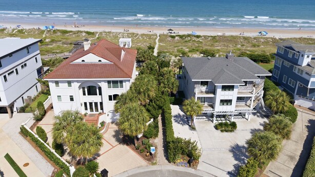 A beachfront property with a large house, a smaller building, and a sandy beach.