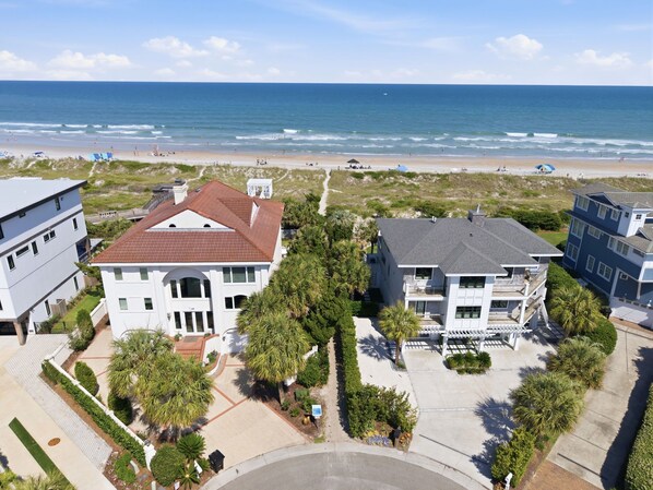 A beachfront property with a large house, a smaller building, and a sandy beach.