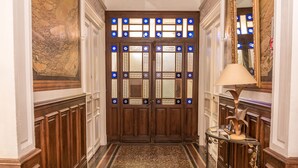 A hallway with a wooden double door, a mirror, and a table with a lamp. -  Villa Celine,  a Bed & Breakfast with four bedrooms, garden and  swimming pool (Saint-Laurent-De-La-Cabrerisse)
