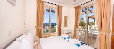 Una habitación de hotel con cama, escritorio, silla y balcón con cortinas.