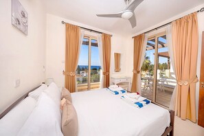 A hotel room with a bed, a desk, a chair, and a balcony with curtains. - Villa With Private Pool Hosting Up To 4 Guests - Great Sea Views. (Coral Bay)