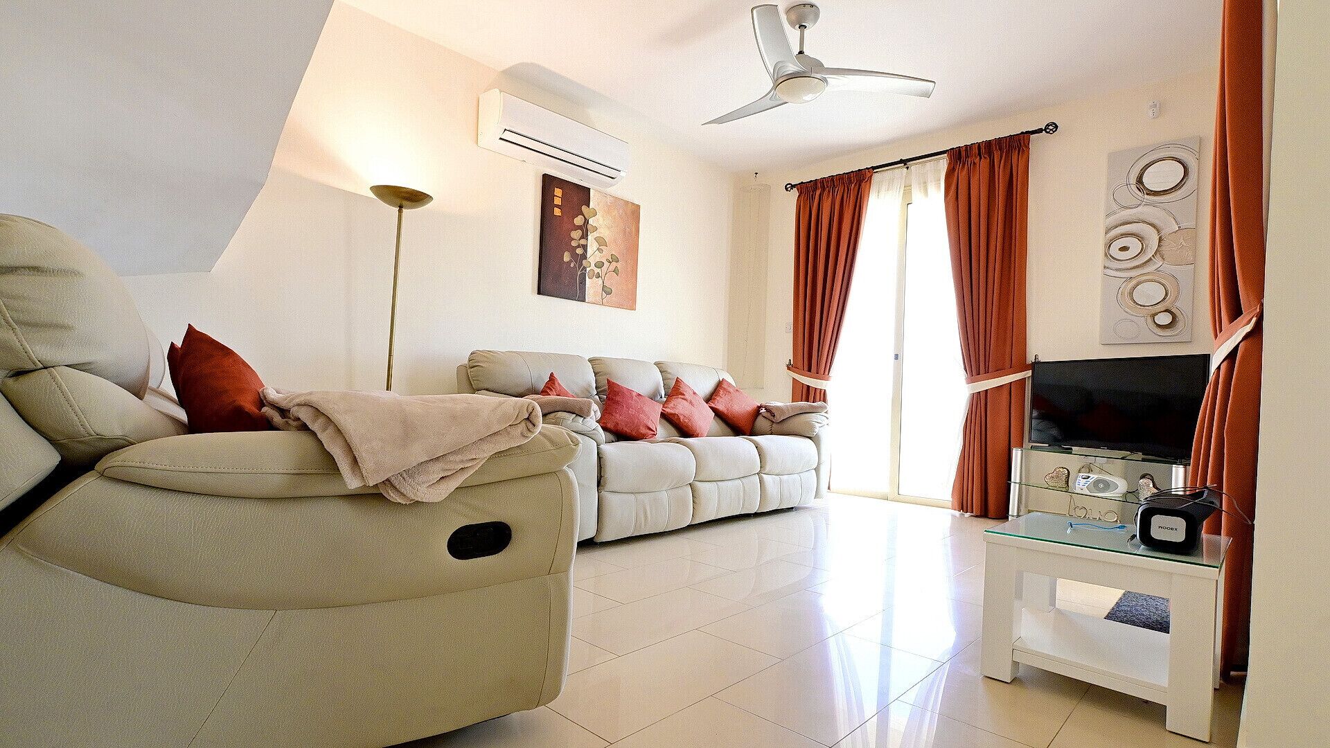 A living room with a sofa, armchair, and a TV stand with a flat-screen TV.