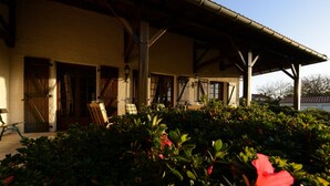 A building with a covered porch, wooden doors, and a bench. - GITE NOLAN *** SPA/SAUNA, 20MN FROM PUY DU FOU, IDEAL WITH FAMILY OR FRIENDS (Saint-Mesmin)