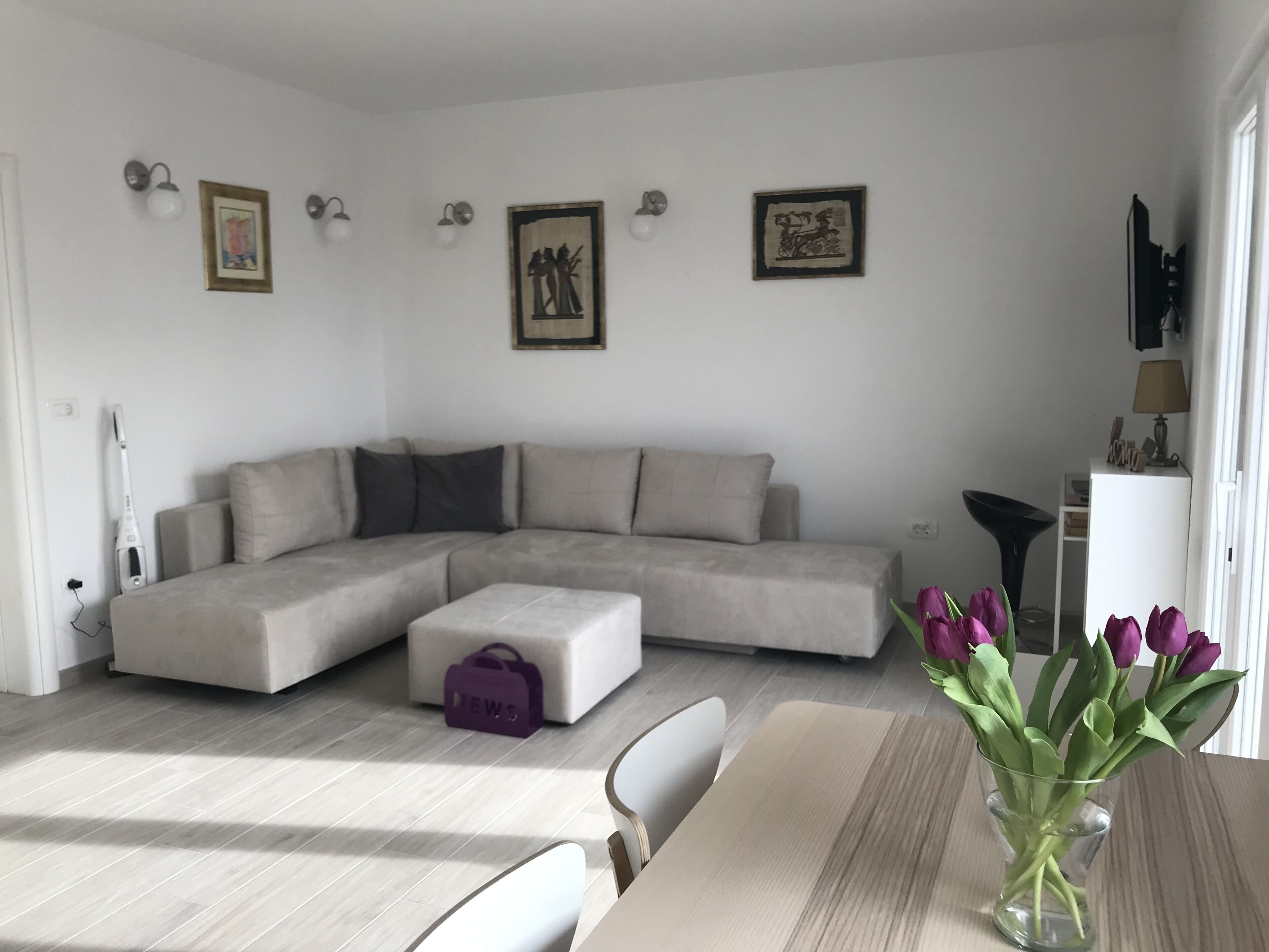 Uma sala de estar moderna com um sofá seccional, uma mesinha e um vaso de flores.