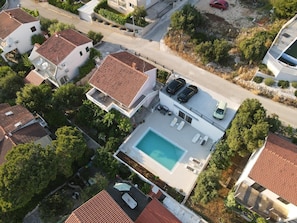 Zona residencial con piscina, varias casas y automóviles estacionados.