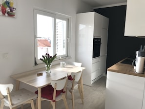 Una cocina moderna con armarios blancos, una encimera de madera y una ventana con persianas.