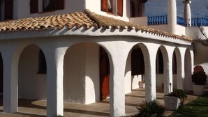 Un bâtiment à la façade blanche, doté de nombreuses arcades et surmonté d’un toit en tuiles.