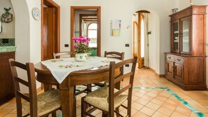 Un coin repas avec une table et des chaises en bois, un vase à fleurs et un buffet.