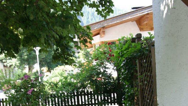 A stone pathway leading to a wooden gate, surrounded by a well-maintained lawn and a white picket fence. - Quiet in the center: apartments The ideal basis for outdoor activities (Oetz)