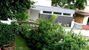 A patio with a stone floor, a wooden table, and chairs. There is a small garden area with a wooden barrel and a gravel circle. - Quiet in the center: apartments The ideal basis for outdoor activities (Oetz)