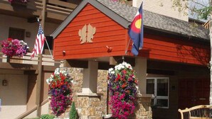 A red building with a stone facade, two flower baskets, and flags. - Eagle Point Resort Vail Condo available December 18-25, 2026 (Vail)