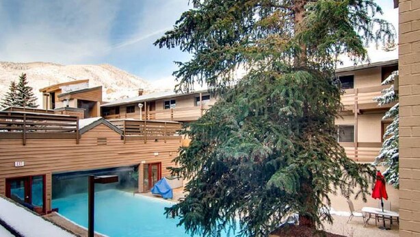 A hotel with a pool area, wooden exterior, and a mountain backdrop. - Eagle Point Resort Vail Condo available December 18-25, 2026 (Vail)