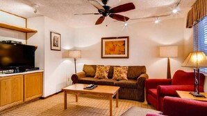 A living room with a sofa, red armchair, wooden coffee table, and a television. - Eagle Point Resort Vail Condo available December 18-25, 2026 (Vail)